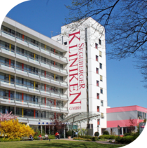 Fassade des Herz und Gefäßzentrums mit grüner Wiese und Rosensträuchen vor dem Gebäude.