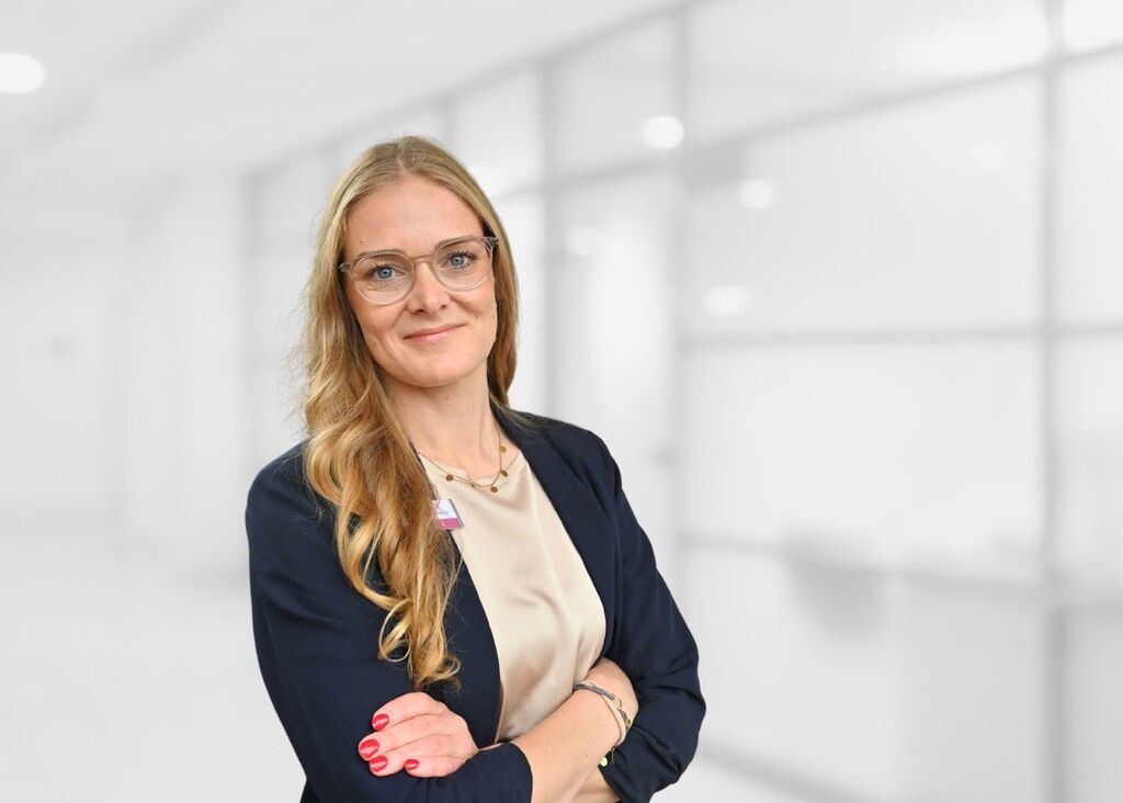 Junge Blonde lächelnde Dame in blauem Blazer und mit Brille