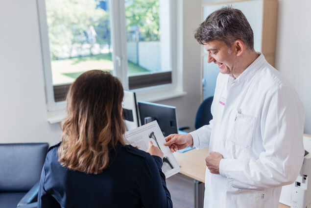 Chefarzt Dr. Inden erklärt Patientin Befunde