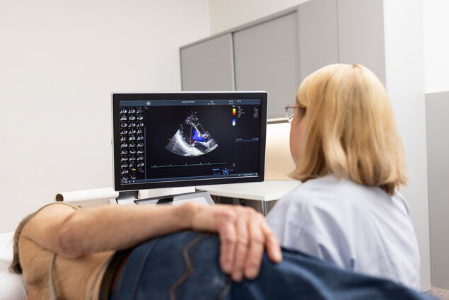 Blonde Ärztin untersucht oberkörperfreien Patienten mit Ultraschallgerät am Herzen