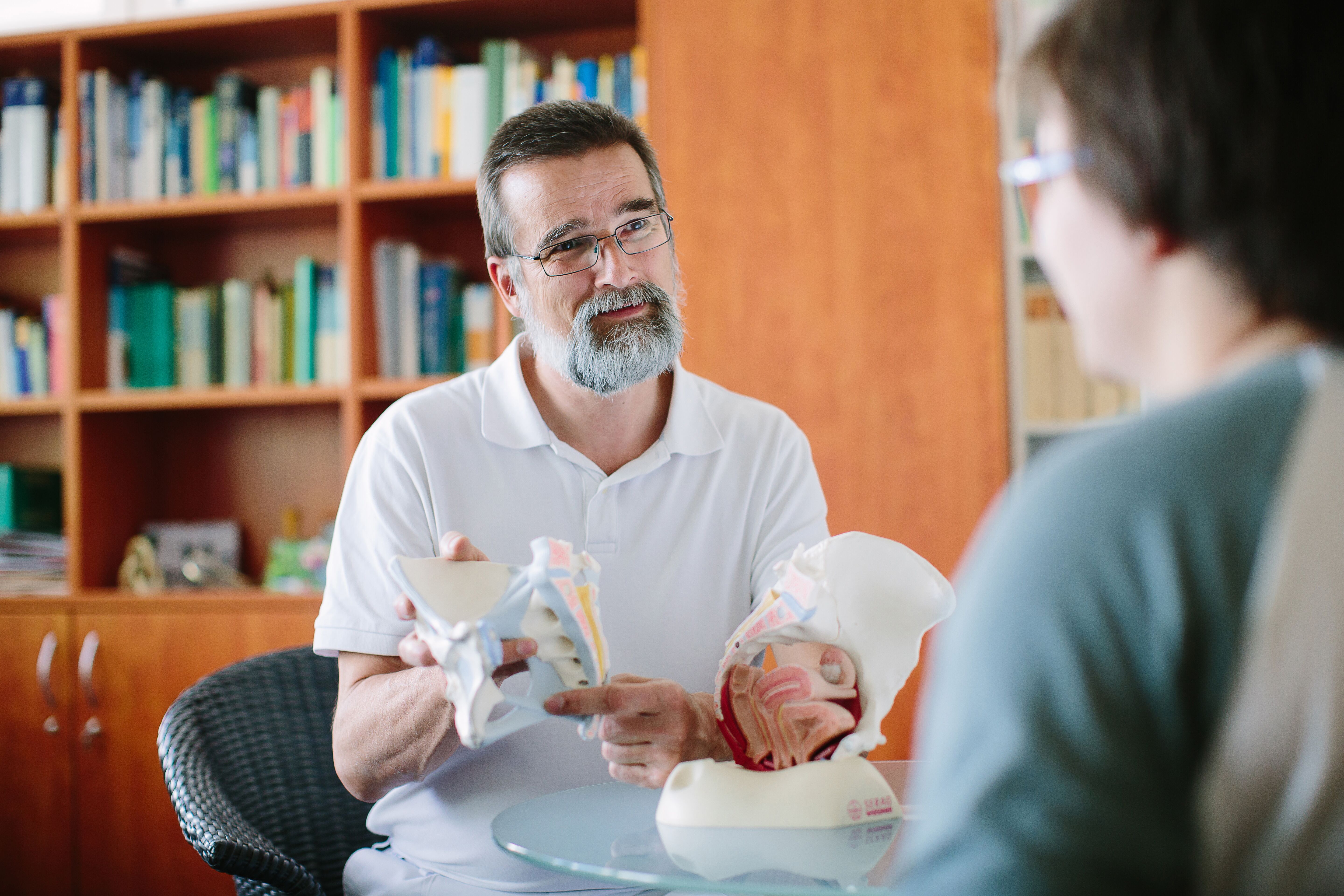 Chefarzt erklärt an einem anatomischen Modell einer Patientin Befunde